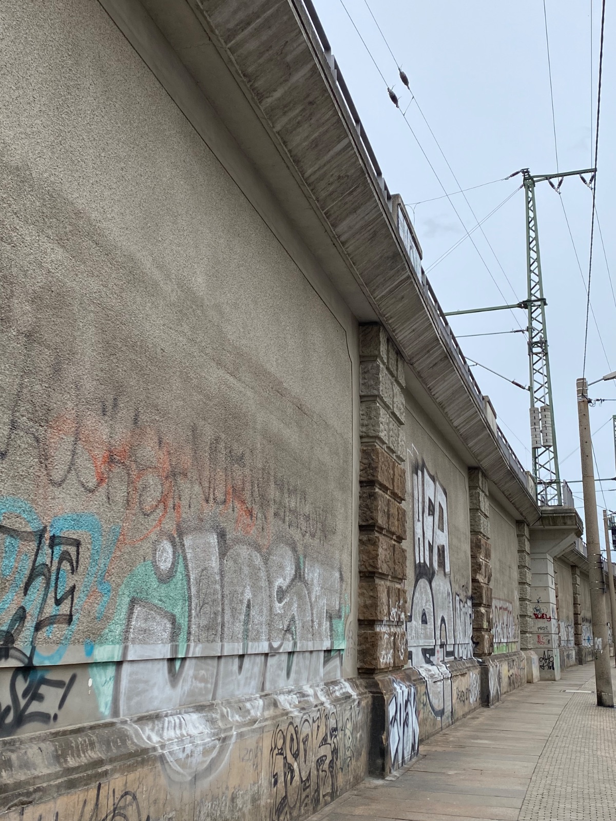 Lange Bahnmauer mit Graffiti in der Dresdner Neustadt, ein Weg führt in die Ferne